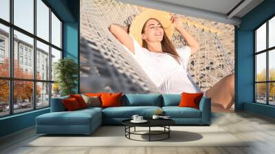 Young woman relaxing in hammock on beach Wall mural