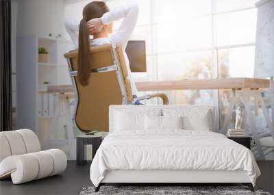 Young woman relaxing in office chair at workplace, back view Wall mural