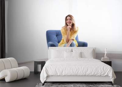 Young woman sitting in armchair at home Wall mural