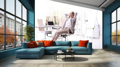 Young woman sitting in armchair at workplace Wall mural