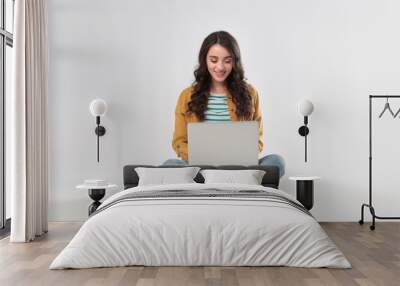 Young woman sitting with laptop on white background Wall mural