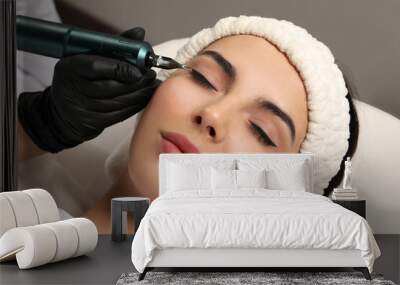 Young woman undergoing procedure of permanent eyeliner makeup on grey background, closeup Wall mural