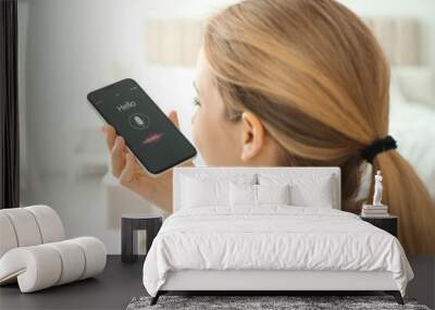 Young woman using voice search on smartphone indoors Wall mural