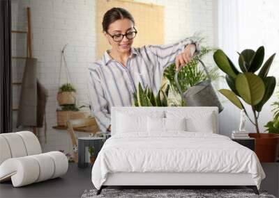 Young woman watering potted plant at home Wall mural