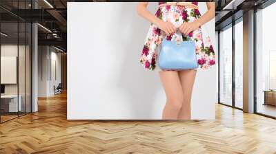 Young woman wearing floral print dress with stylish handbag on light background, closeup. Space for text Wall mural