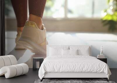 Young woman wearing stylish sneakers indoors, closeup Wall mural