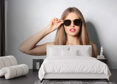 Young woman wearing stylish sunglasses on light background Wall mural