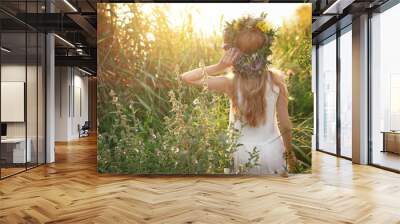 Young woman wearing wreath made of beautiful flowers outdoors on sunny day, back view Wall mural