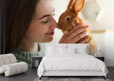 Young woman with adorable rabbit indoors, closeup. Lovely pet Wall mural