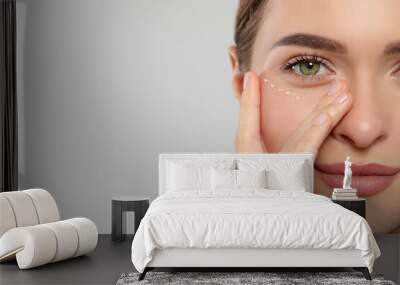 Young woman with cream around eye on white background, closeup. Space for text Wall mural