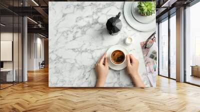 Young woman with cup of delicious hot coffee at table, top view Wall mural