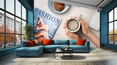 Young woman with cup of delicious hot coffee at table, top view Wall mural