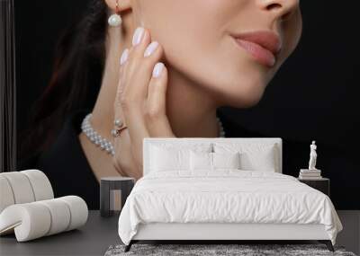 Young woman with elegant pearl jewelry on black background, closeup Wall mural