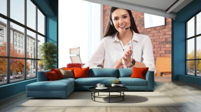 Young woman with headset looking at camera and using video chat in home office Wall mural