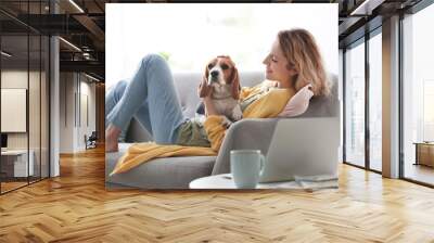 Young woman with her dog on sofa at home Wall mural