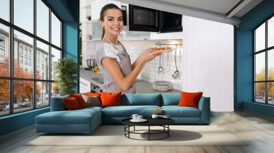 Young woman with plate of croissants near microwave oven in kitchen Wall mural