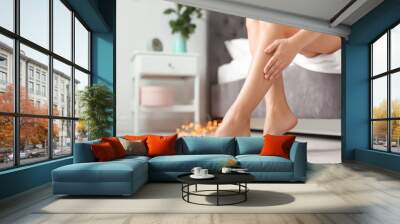 Young woman with sexy legs sitting on bed at home Wall mural