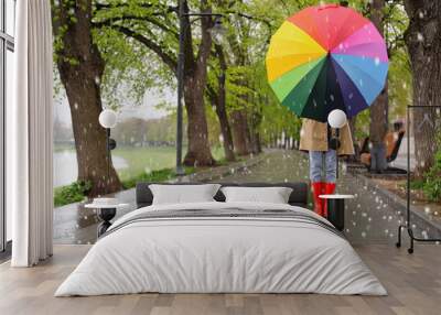 Young woman with umbrella walking in park on rainy day with hail Wall mural