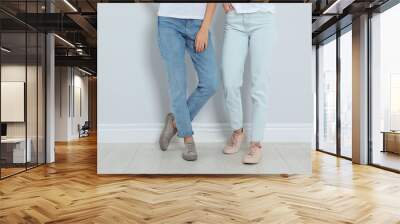 young women in stylish jeans near light wall, closeup Wall mural