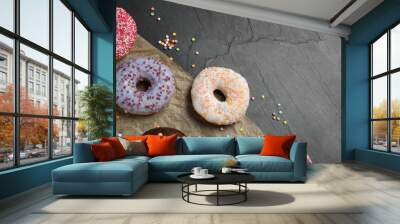 Yummy donuts with sprinkles on dark background, flat lay. Space for text Wall mural