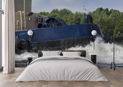 Bow of a tugboat sailing true the water. Big wave in front. Wall mural