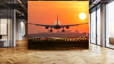 Passenger plane is landing during a wonderful sunrise. Wall mural