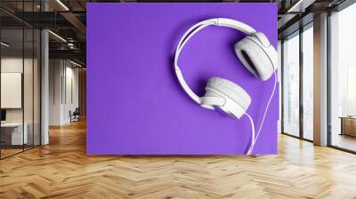 White headphones over a bright purple background Wall mural