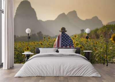 A man is walking into the sunflower field with United State flag as in independence day and freedom concept with landscape mountain background while sunset. Wall mural