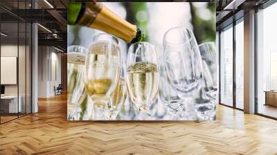 the waiter pours champagne in glasses on the street - wedding catering - look from below Wall mural