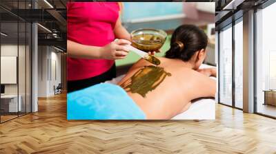 Young woman is put on a mask on her back in spa salon. natural mask (scrub) with sea salt, extracts of herbs and spirulina Wall mural