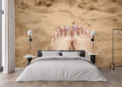 Woman feet with light pink toenails on the sand Wall mural