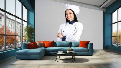 Chef woman wearing uniform and cap standing arms crossed and posing over isolated grey background. Occupation concept Wall mural