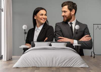 Confident happy young business partners looking at each other while posing isolated on grey background. Business concept Wall mural