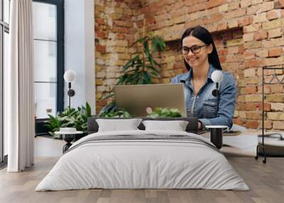 Young positive woman working at office desk Wall mural