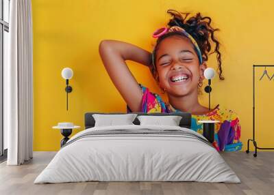 Smiling girl with curly hair and bright shirt on yellow background. Wall mural