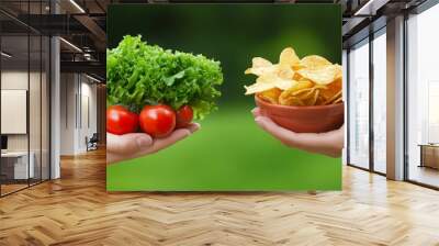 One hand holding bowl of vegetable salad, other holding chips. Healthy natural organic fresh vegetarian food vs unhealthy processed fast junk food Wall mural