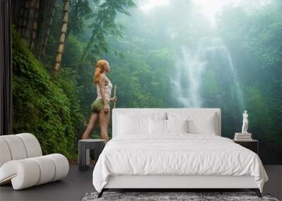 Female adventurer looking at waterfall Wall mural