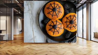 Fun Halloween spider web pumpkin pancakes with blackberry spiders. Overhead view on a black plate against a rustic white wood table background - generative ai Wall mural