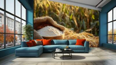 A table with grain in a burlap bag and wheat flour in a bowl is surrounded by ripe cereal fields. Wall mural