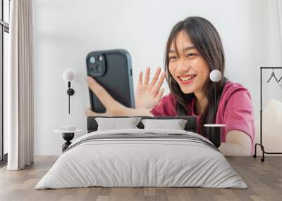 Asian young woman using mobile phone virtual video call remotely in house. Teenager girl sitting on bed and using smartphone communicating online in bedroom. Technology device concept  Wall mural