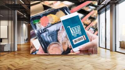 Online order grocery shopping on touch screen for ready meal food concept. Woman hand holding smart phone and scanning barcode for delivery service or take out at home. Business and technology. Wall mural