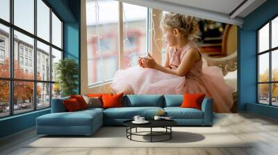 Cute little girl sitting by the window Wall mural