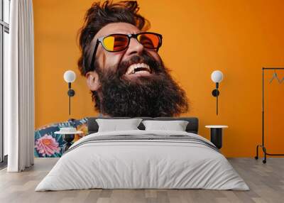 A bearded man, dressed in a floral shirt, poses against a bright orange background, exuding a unique blend of casual and eccentric style, highlighted by his wild beard. Wall mural