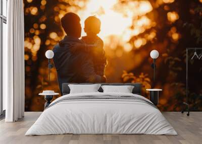 A heartwarming silhouette of a man holding a young child against a backdrop of a golden sunset, surrounded by lush greenery, evoking feelings of love and connection. Wall mural