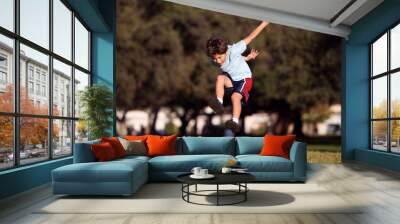 Happy young boy jumping and playing in the park Wall mural