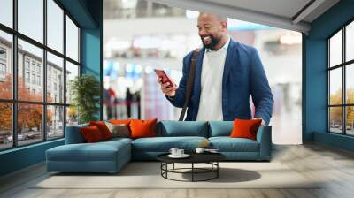 Businessman, phone and smile with luggage for travel, journey or texting in communication at the airport. Happy black man, person or employee holding smartphone for chatting, traveling or work trip Wall mural