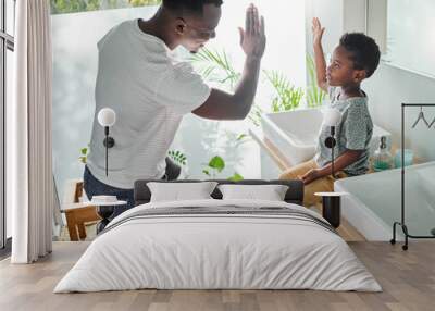 Encourage your child to follow good hygiene practices. High angle shot of a father giving his son a high five in a bathroom at home. Wall mural