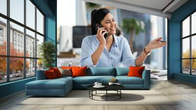 Its your passion that will lead you to success. Shot of a young businesswoman talking on a cellphone while working on a computer in an office. Wall mural