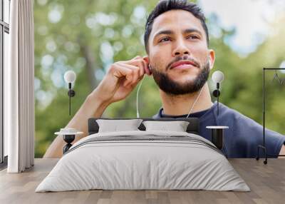 Pump the playlist thatll make you run further. Shot of a sporty young man listening to music while exercising outdoors. Wall mural