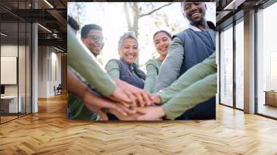 Teamwork, motivation and huddle with senior friends hiking together in the forest or woods from below. Fitness, exercise or nature with a mature man and woman friend group putting hands in a circle Wall mural